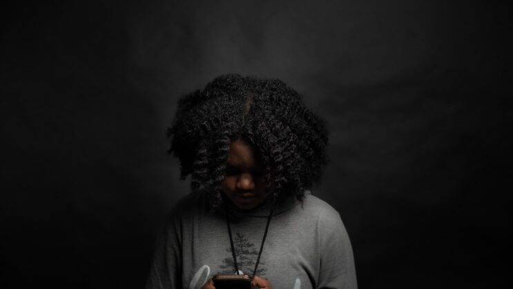 woman in gray long sleeve shirt holding black smartphone