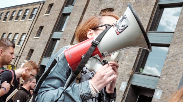 woman holding red and white megaphone standing near building